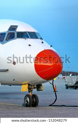 Closeup of red aircraft nose with pilot cabin against blue sky