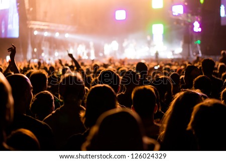 Shot of some cheering fans during a life concert, visible noise due high ISO, soft focus, shallow DOF, slight motion blur
