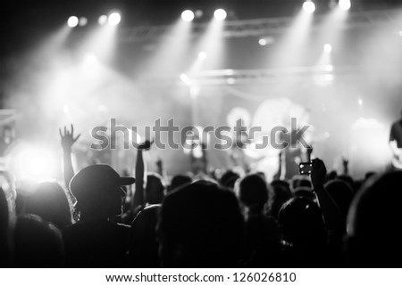 Shot of some cheering fans during a life concert, visible noise due high ISO, soft focus, shallow DOF, slight motion blur