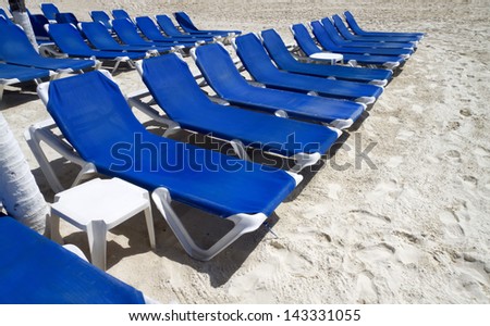 Rows of blue several lounge chairs on the beach