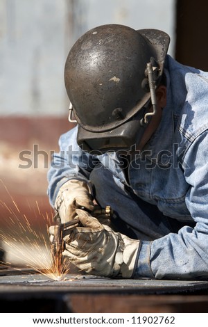 a man using burning torch to cut steel