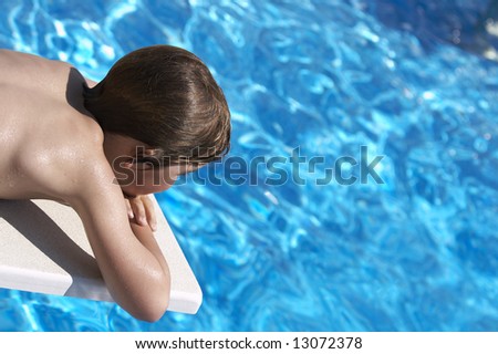 a boy looking into a pool from the diving board