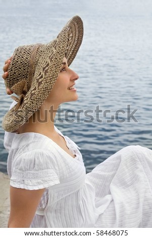 Happy young girl in the bonnet near the sea
