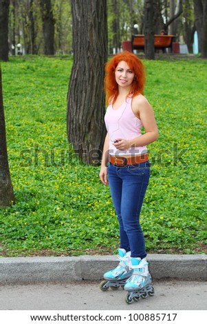 Ginger girl on roller skates listening to music in the park