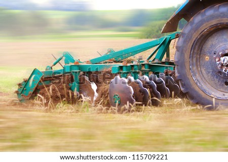 Tractor ploughing up the field. Motion blur was done for effect to emphasize speed
