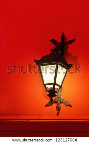 Wall lantern on a red wall at night