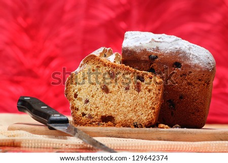 Cut cake with raisins on a breadboard over a cup of tea on the background