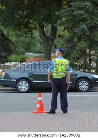 KIEV - JUNE 15: Ukrainian police officer standing by the road in lime-colored uniform and holding a rod on June 15, 2013 in Kiev, Ukraine