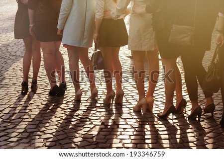A row of young pretty women on high heels standing on block paving