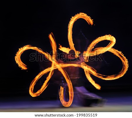 Artist juggling with two burning poi\'s at fire performance. Long exposure causing painting with light