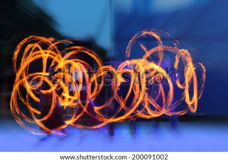 Artists juggling with two burning poi\'s at fire performance. Long exposure causing painting with light