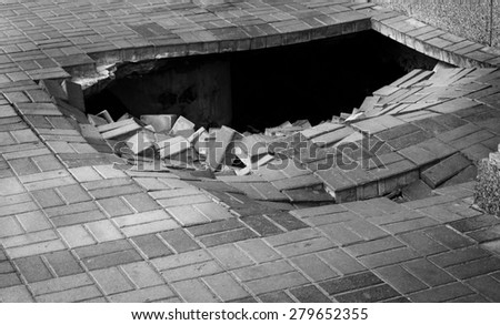 A hole in pedestrian pavement road