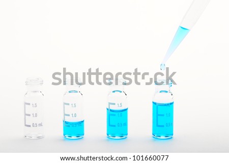 Chemical research - sample preparation: sample vials for chromatography filled with different volumes of blue liquid and a pipette tip with a droplet. Isolated on white, clipping path included