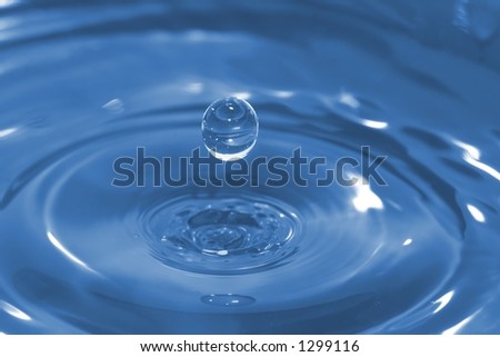High-speed photo of a water drop frozen in time after it has impacted and rebounded a body of water.