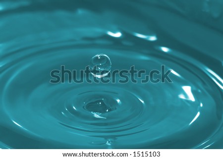 High-speed photo of a water drop frozen in time after it has impacted and rebounded a body of water.