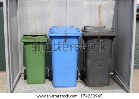 Three colourful dustbins in the public area of a port
