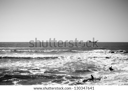 Silhouette of the surfer riding a wave and doing tricks, black and white photo