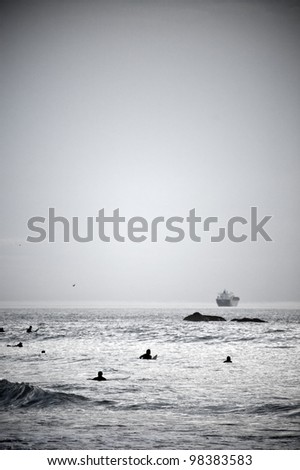 Black and white vertical photo of the surfers in the sea waiting for the waves