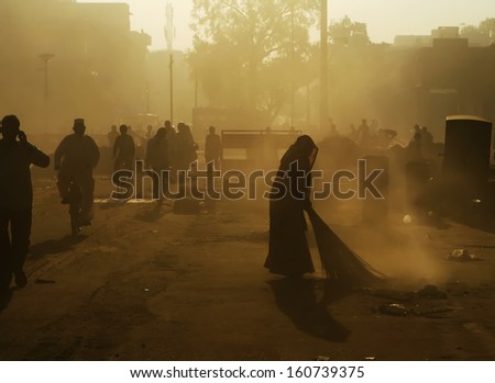 Silhouette of a woman broom sweeping the road in India 1