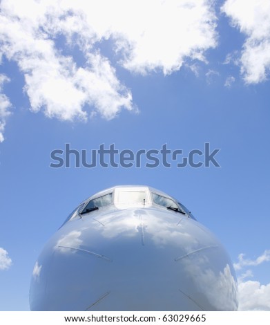 nose of plane with a blue sky and clouds in background
