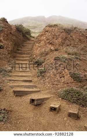 Wooden steps on a mountain path during a foggy day.