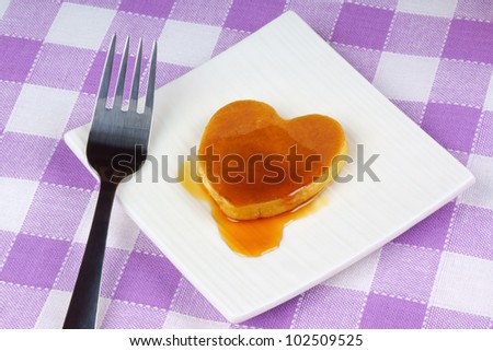 Mini heart-shaped pancake with syrup on a white dish with fork. A perfect breakfast for Valentine\'s Day