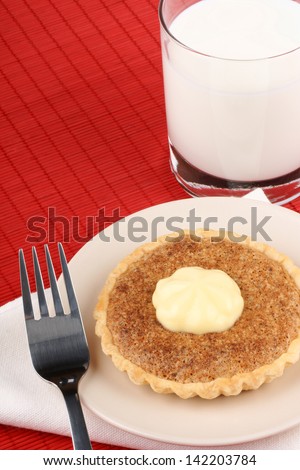 Walnut mini tart with mascarpone a dessert fork and a glass of milk over a red background