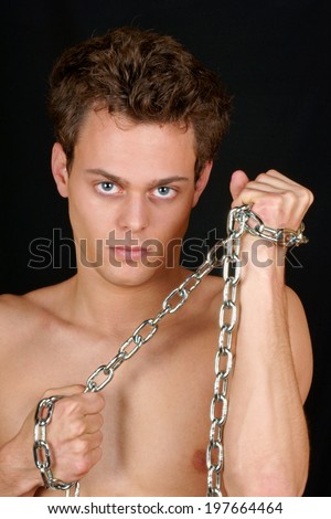 Shirtless young caucasian man holding a chrome chain over a black background.