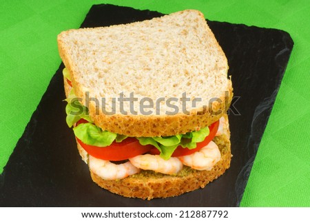 Closeup of a sandwich with shrimps, pesto, lettuce and tomato