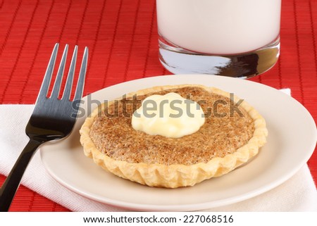 Walnut mini tart with mascarpone a dessert fork and a glass of milk over a red background