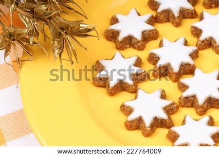 Cinnamon star cookies (in german Zimtsterne) are typical german and swiss Christmas cookies made of almonds. Over a yellow plate.