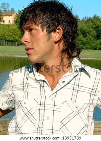 Handsome young man at the park in front of a pond