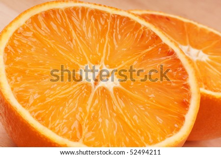 Closeup of an orange cut into two halves over a wooden cutting board