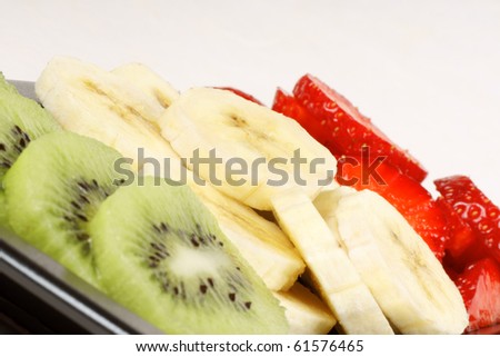 Closeup of slices of kiwi, banana and strawberry. It could represent an organic italian flag.