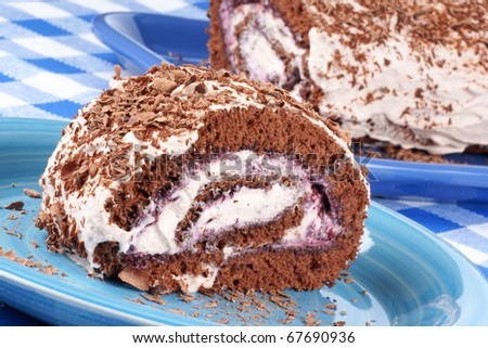 Chocolate swiss roll cake with berries marmalade and whipped cream over a chequered background