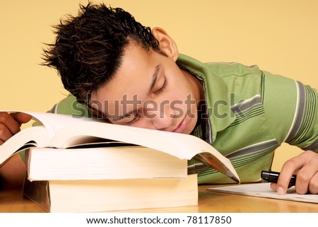 Closeup of an hispanic 19 years old student sleeping on books instead of studying.