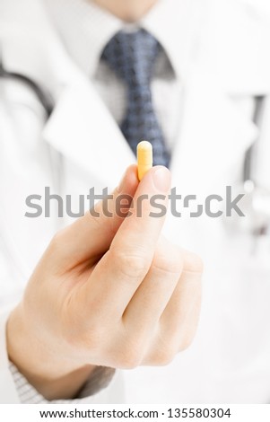 Medical doctor holding one pill with right hand fingers