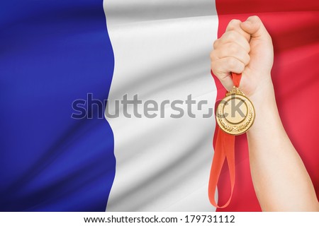 Sportsman holding gold medal with flag on background - French Republic