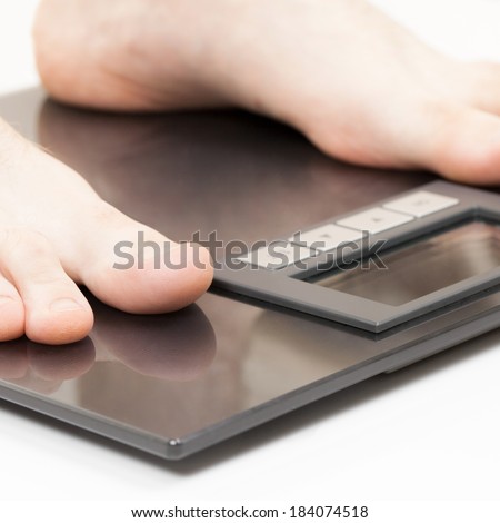 Man standing on weight scales with bare foot - 1 to 1 ratio