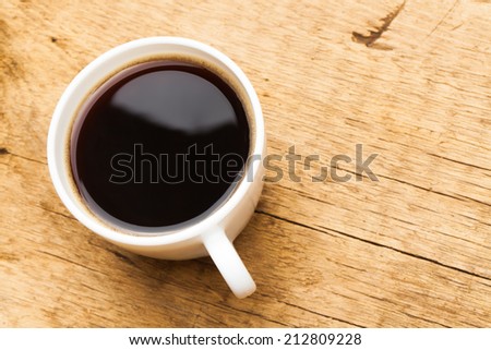 Coffee in white ceramic cup on wooden table - view from top