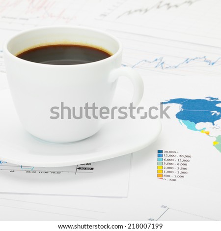 Coffee cup over world map and financial documents - 1 to 1 ratio