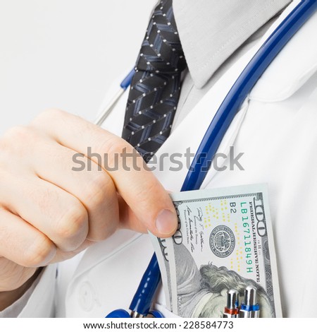 Medical doctor putting money into his pocket - studio shoot