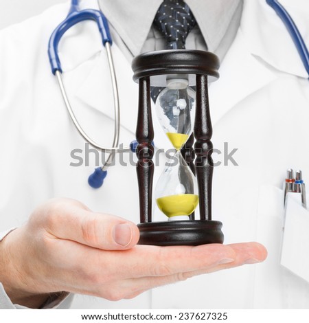Medical doctor with hourglas in his hand - medical aid concept