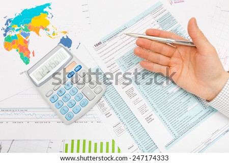 US 1040 Tax Form, calculator and male hand with silver pen in it