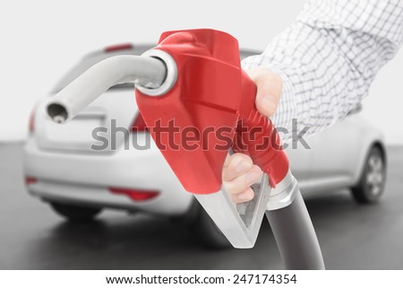 Red color fuel pump gun in hand with grey car on background