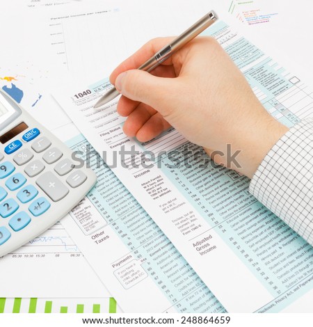 Male filling out 1040 US Tax Form using silver ball pen - studio shot