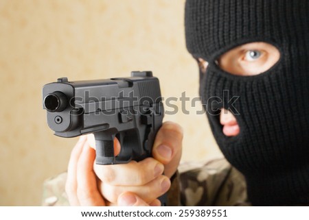 Man in black mask holding gun before him