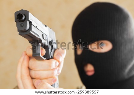 Man in black mask holding gun and ready to use it