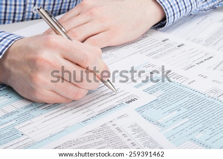 Taxpayer filling out 1040 Tax Form - studio shot