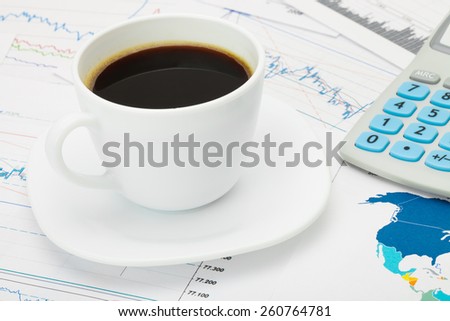 Coffee cup and calculator over world map and some financial charts - business concept